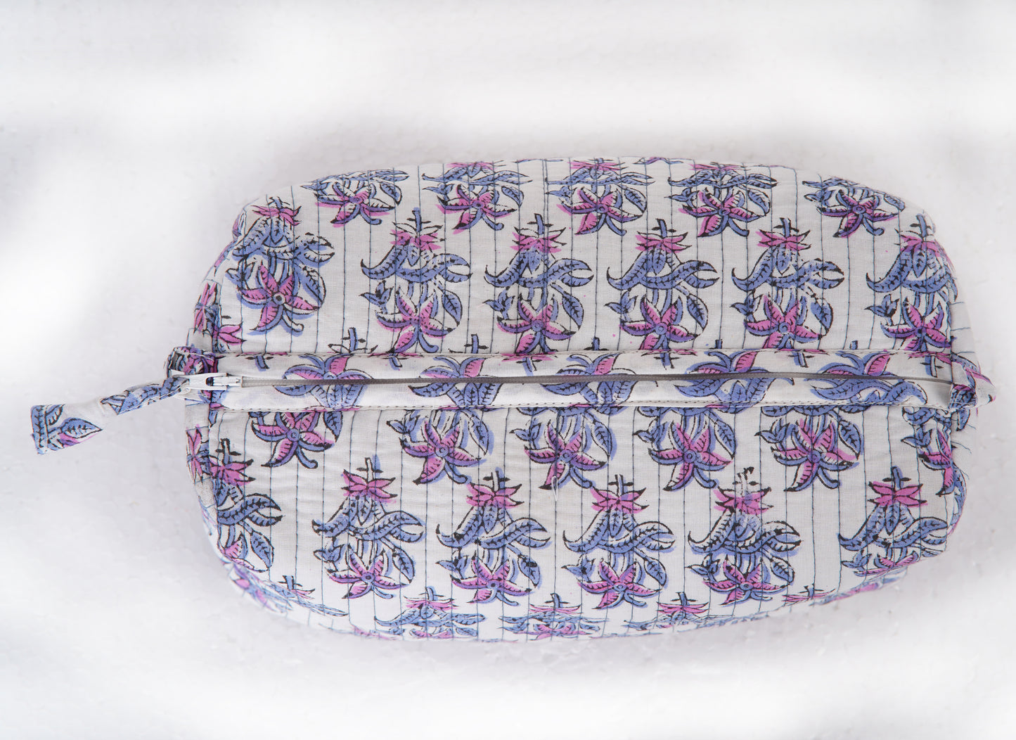 Close-up of hand block printed lotus design in purple and pink on a toiletry pouch