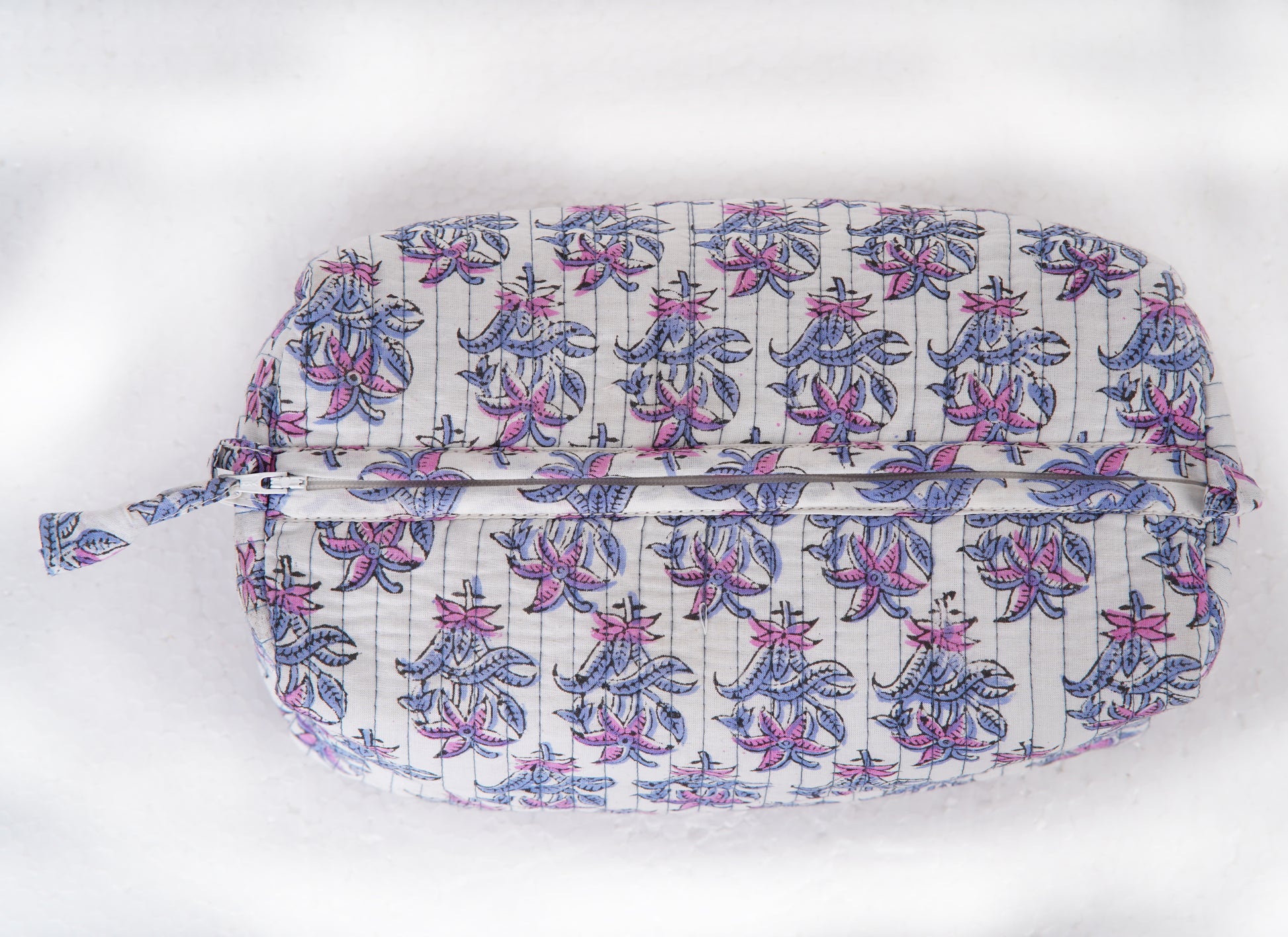 Close-up of hand block printed lotus design in purple and pink on a toiletry pouch